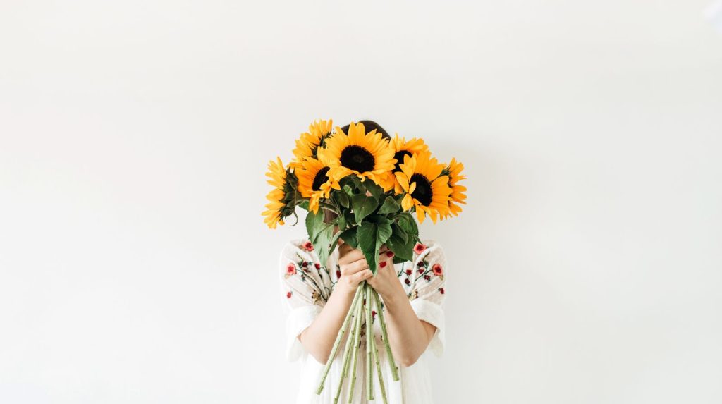 Persona sujetando un ramo de girasoles amarillos para regalar y dar las gracias
