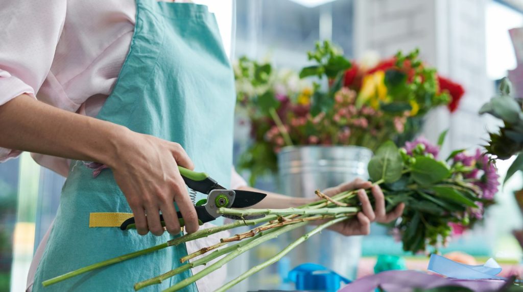 Florista cortando los tallos de un ramo de flores