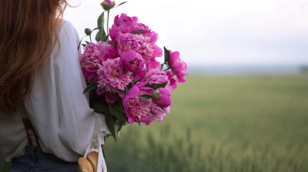 Mujer con ramo de peonias en color rosa