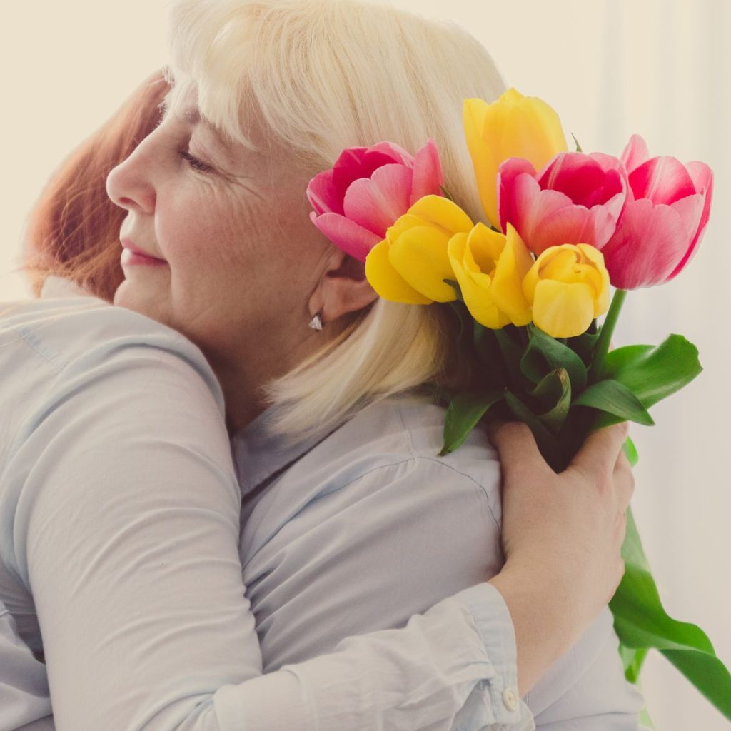 hija abrazando a su madre con flores