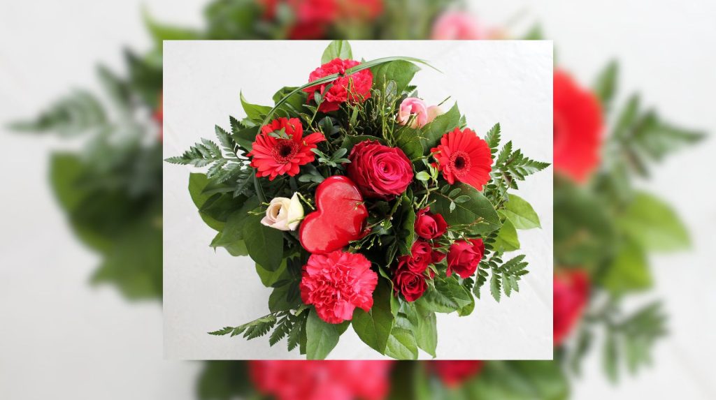 ramo de flores rojas con rosas y gerberas con detalle en forma de corazón