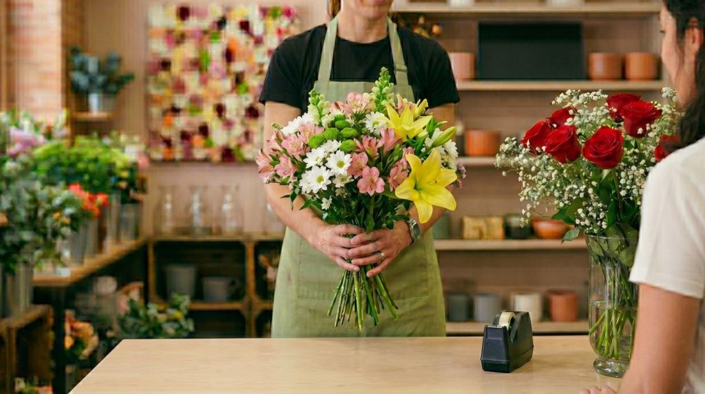 Florista entregando un ramo variado de colores en lugar de un ramo clásico de rosas rojas para un cumpleaños
