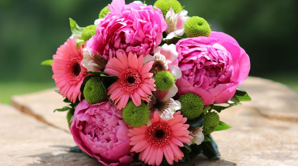 Ramo de flores con peonías rosas y gerberas sobre una superficie de madera