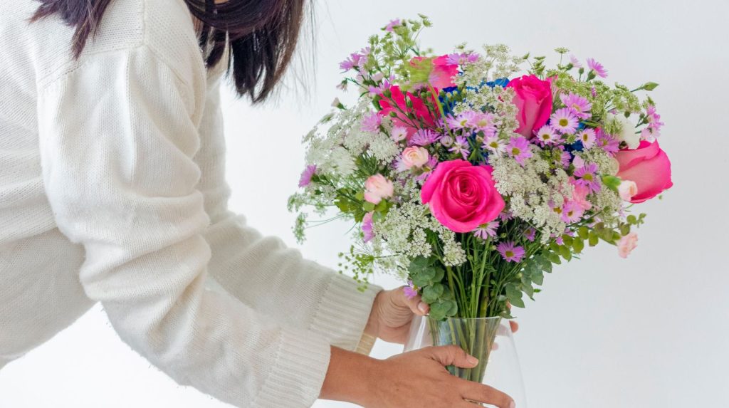 Persona colocando un ramo de flores en casa tras cortar los tallos.