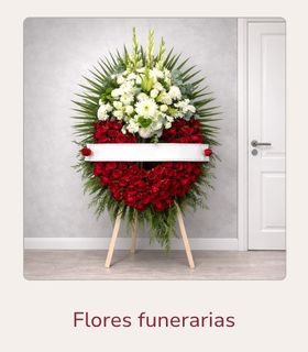 Corona funeraria de rosas rojas y cabecero de flores blancas sobre soporte.