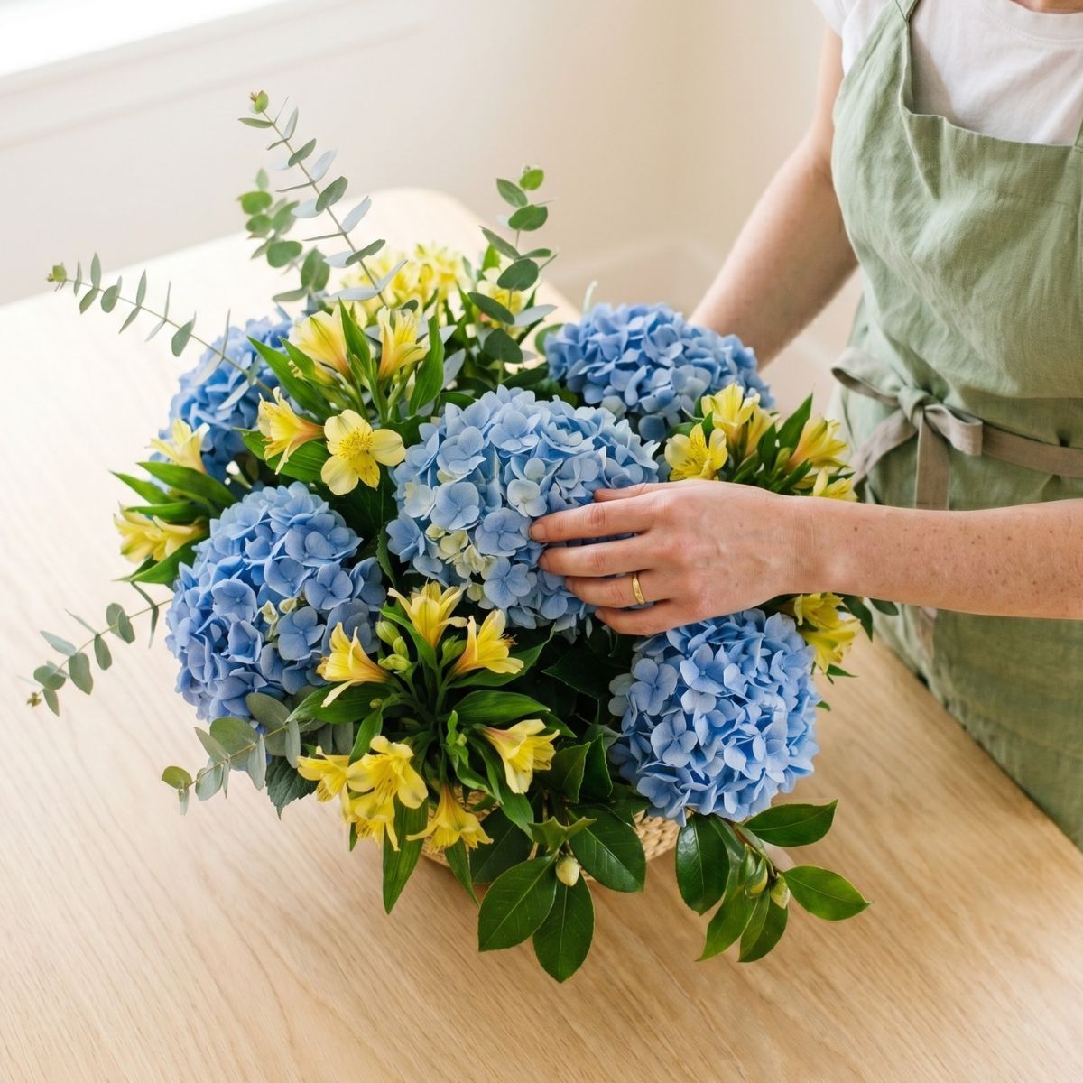 Cesta de flores de temporada Florista haciendo cesta de flores de temporada como las hortensias acompañadas de alstroemerias amarillas y verdes variados.